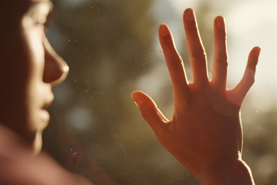 Photo of person with hand against the glass of a window