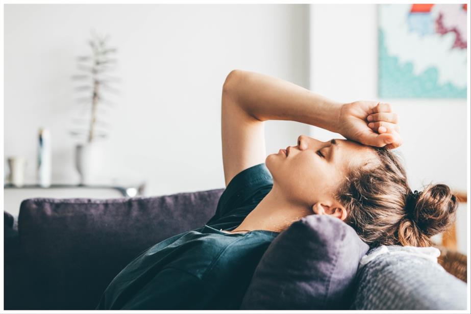 A woman lying back with eyes closed on a sofa