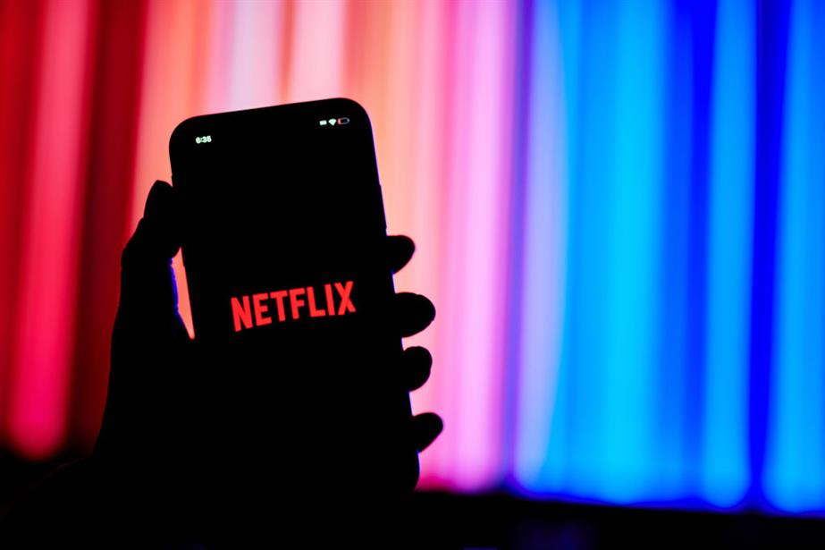 Hand holding smart phone displaying Netflix logo