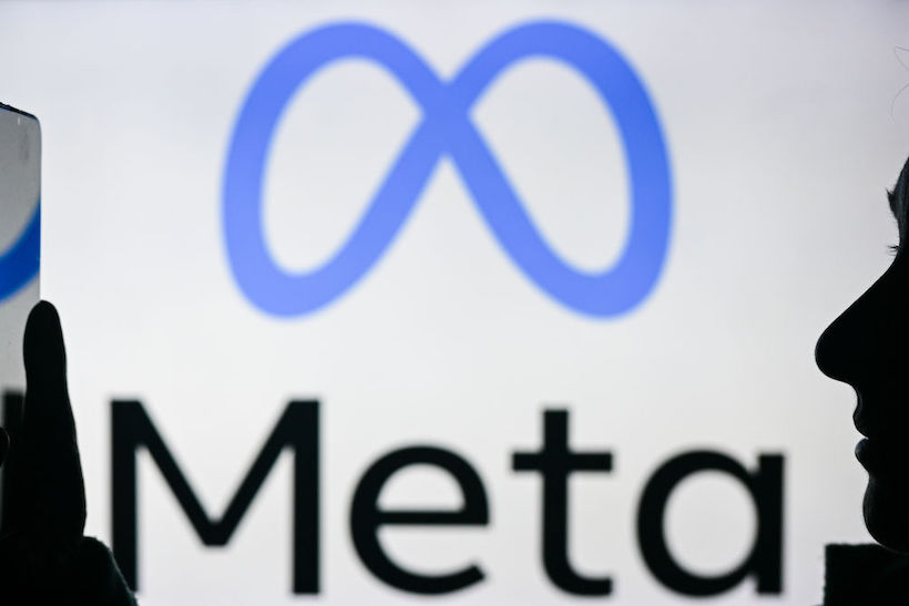 Person holding smart phone in front of Meta logo
