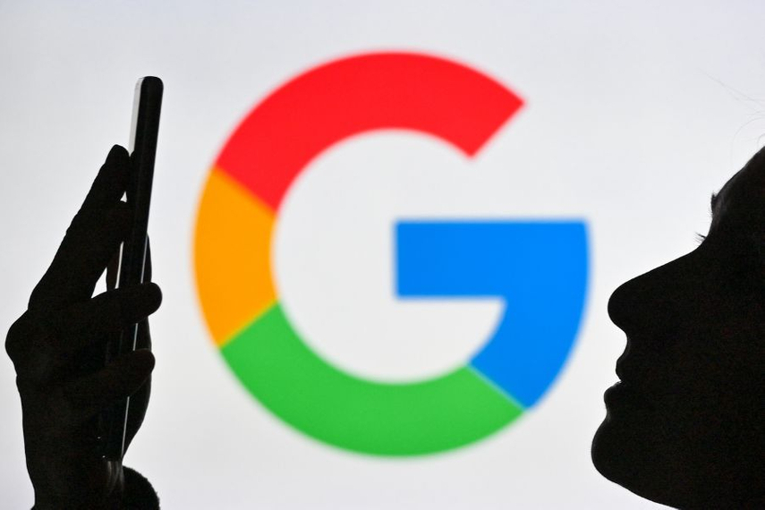 Google 'G' logo in background with silhouette of face looking at smartphone in foreground (©GettyImages)