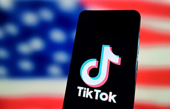 Stock art of a smartphone with the TikTok logo on it in front of an American flag